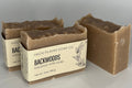 Three bars of soap in cardboard packaging with 'Backwoods' label on a neutral background