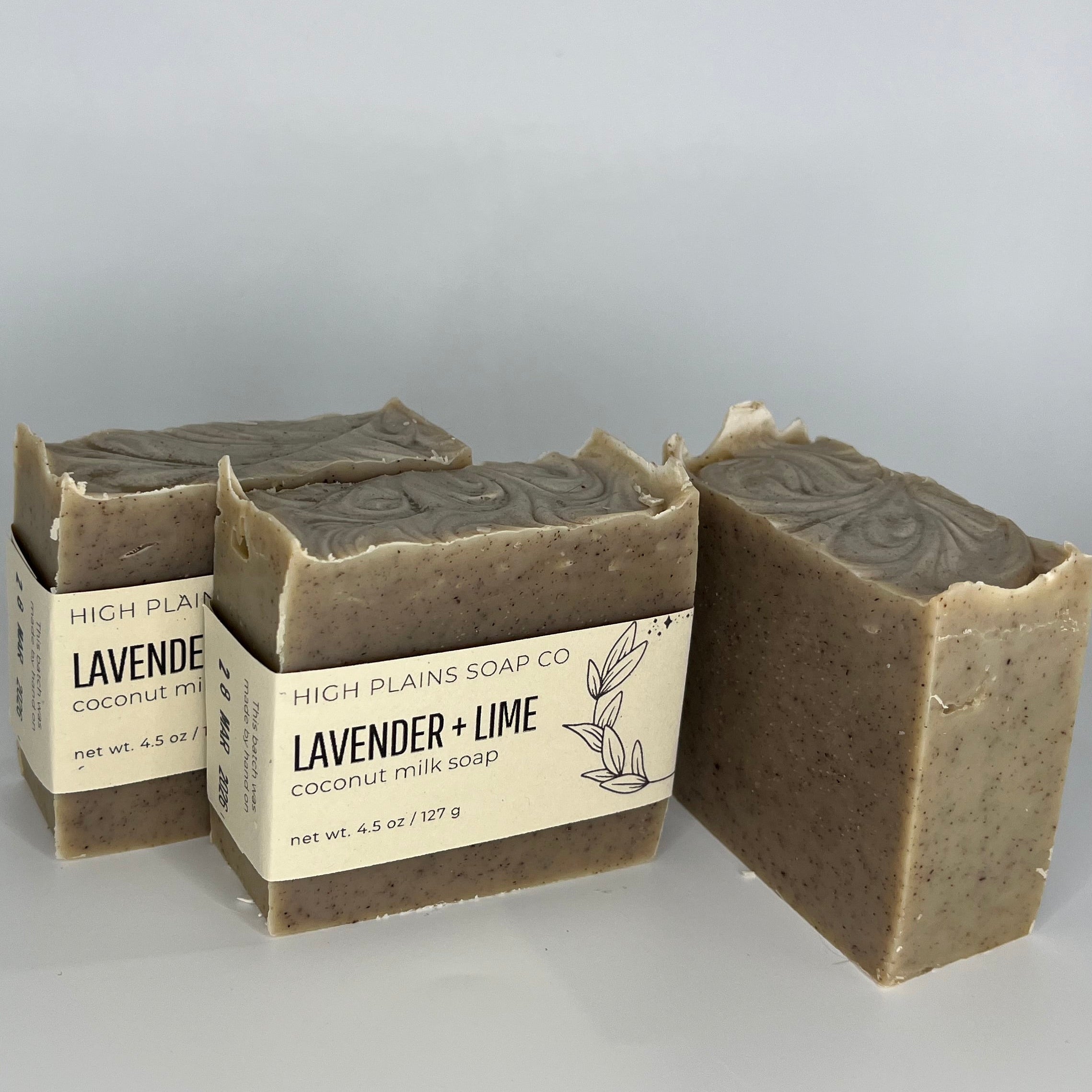 Three bars of soap with packaging on a light gray background