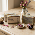 Wooden surface with soap, a brush, and flowers in a jar.